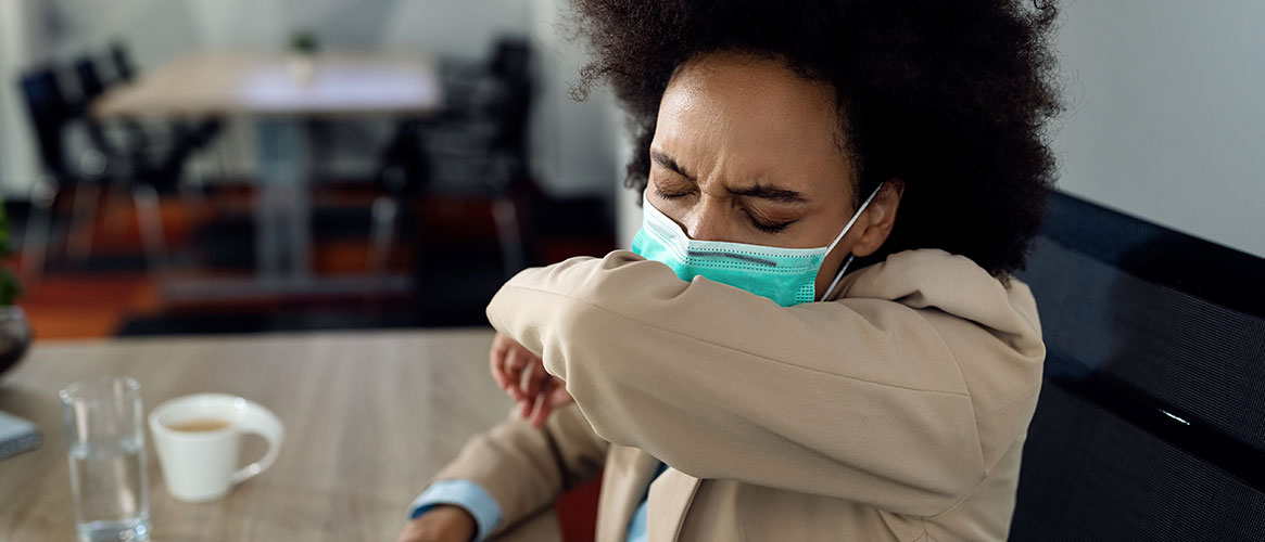 Employee coughing into their elbow to minimize potential spread of tuberculosis