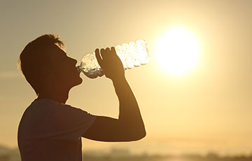 Outdoor worker drinking water while taking a break from work in hot weather Outdoor worker drinking water while taking a break from work in hot weather